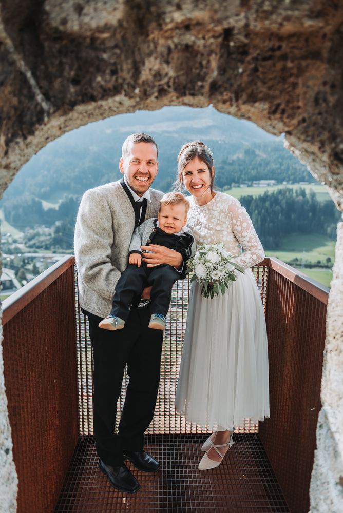 Brautpaar mit Kind in einem Burgfenster mit Blick ins Tal