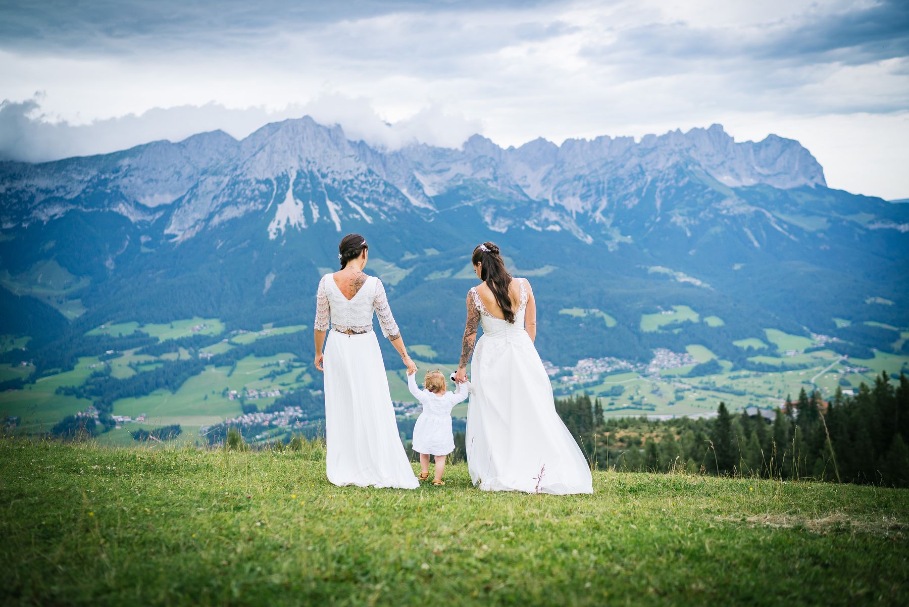 Zwei Bräute mit ihrem Kind auf einer Wiese vor dem Wilden Kaiser