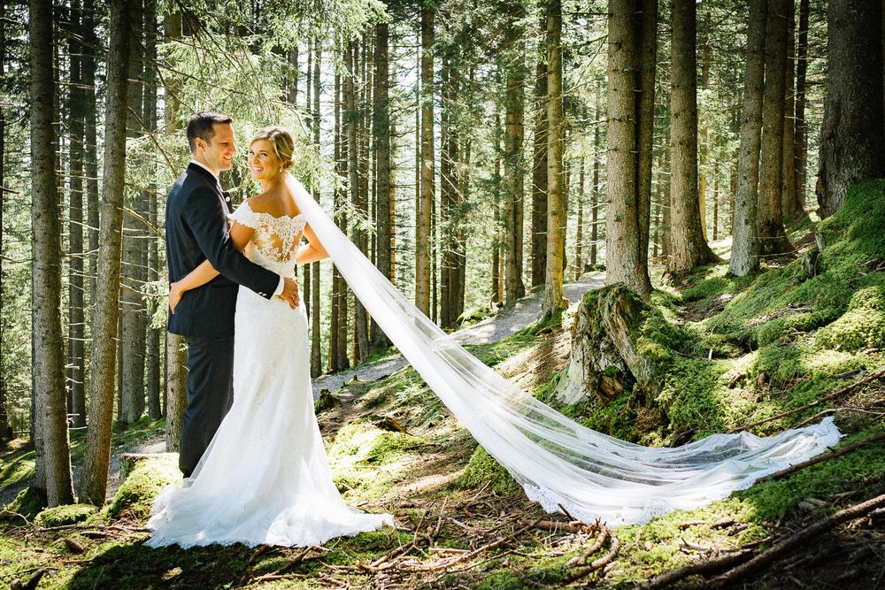 Brautpaar im Wald mit langem Schleier im Licht